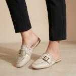 Mules plates style mocassin avec boucle décorative et détails perforés